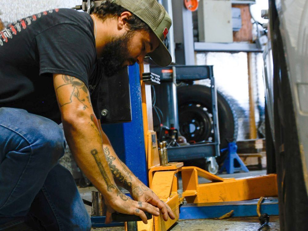 Technician setting the lift arms under a customer vehicle at an auto repair shop in North Little Rock, Arkansas