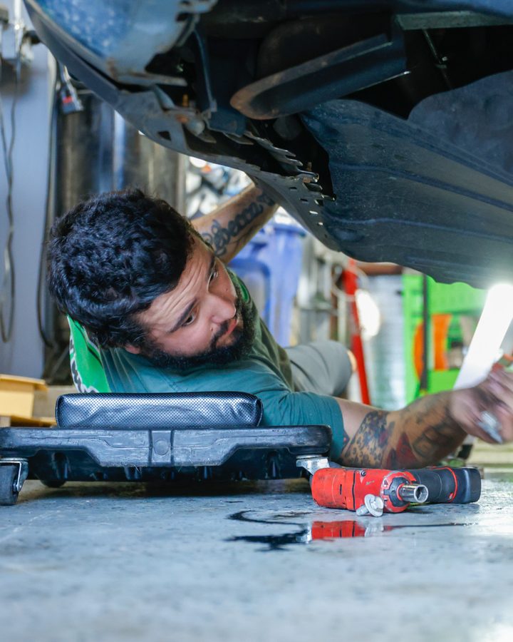 Technician inspecting underneath a vehicle with a work light during a check engine light diagnosis in North Little Rock, Arkansas