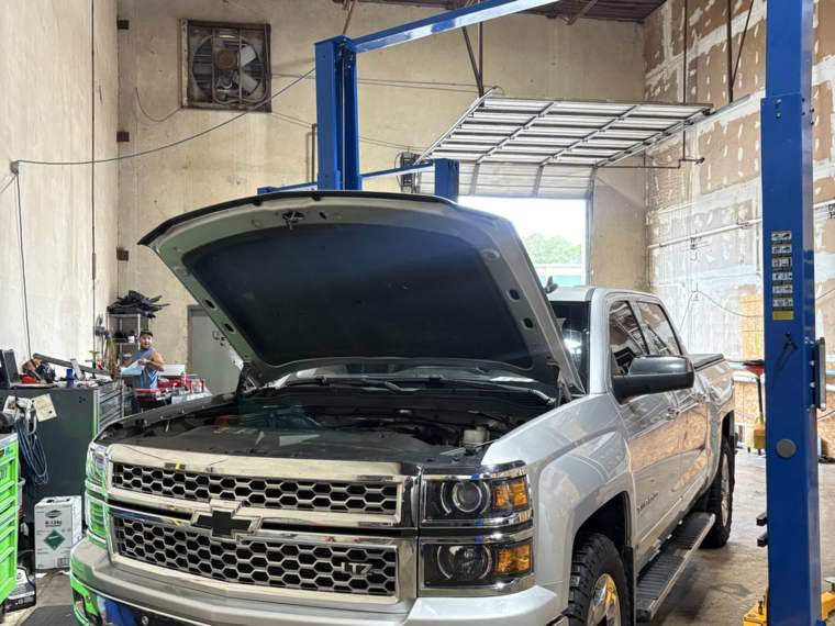 Chevy Silverado 1500 with the hood up on a two-post lift for repair in North Little Rock, Arkansas