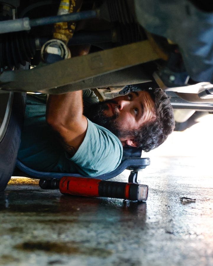 Technician working underneath a GM truck at an auto repair shop in North Little Rock, Arkansas